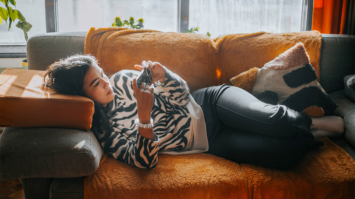 A teenage girl scrolls through social networks alone on her phone.